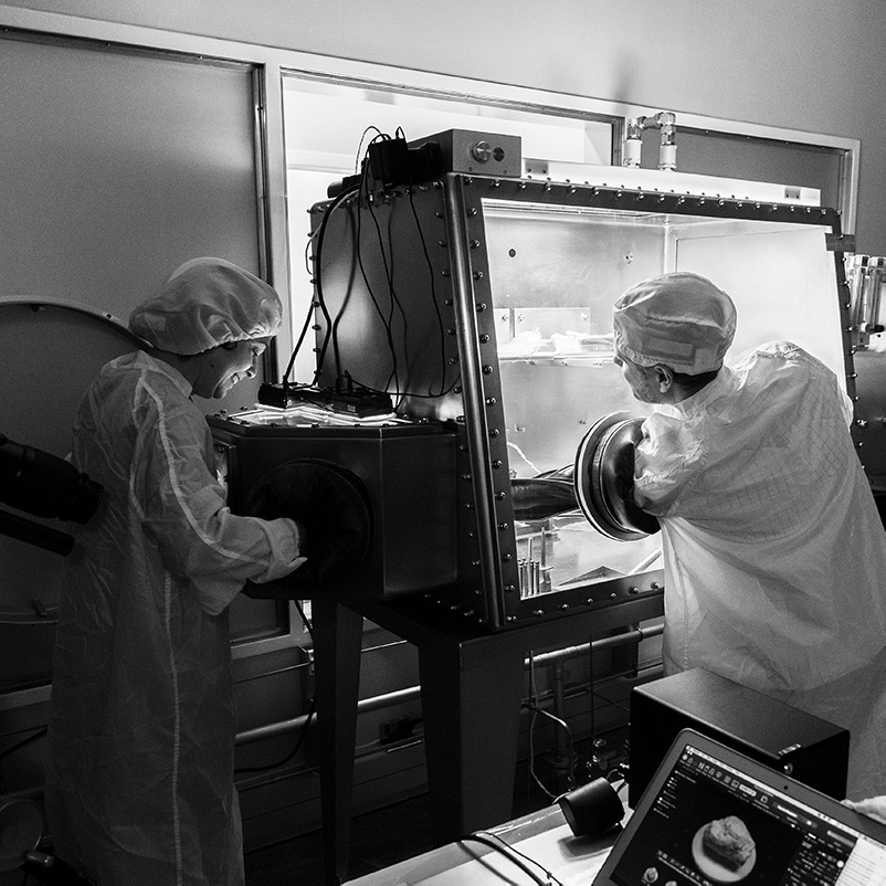 Two scientists in a clean room using a sample cabinet